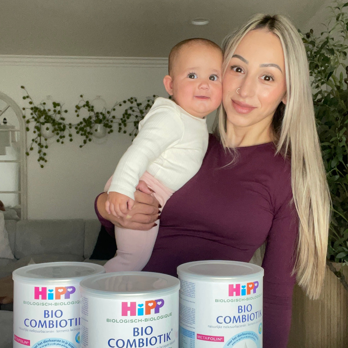 Kseniia holding her baby beside three cans of HiPP Dutch